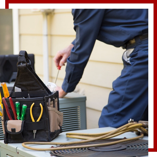 hvac technician wearing blue uniform repairing hvac unit using screwdriver